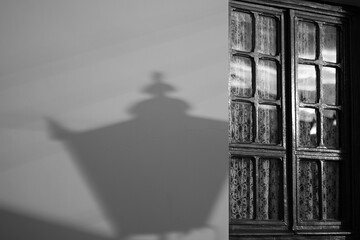 Antique window detail and old lamppost shadow in black and white
