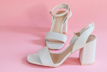 cream female sandals on a pink paper background, closeup side view.