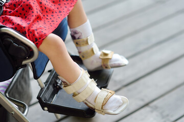 Disabled girl sitting in wheelchair. On her legs orthosis. Child cerebral palsy. Disability....