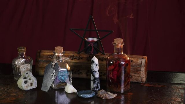 Wiccan altar with burning incense, pentagram, crystals, herbs and love potion