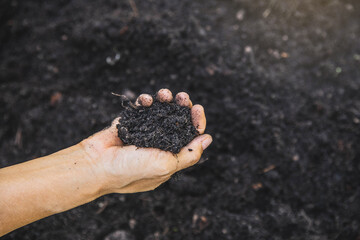 Hand holding soil,Hand dirty with soil. Bunch of good soil in hands on ground background. Closeup hand of person holding abundance soil for agriculture or planting peach concept.