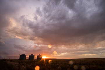 Colorful sunset in Idaho with grain bins and water drops on lens