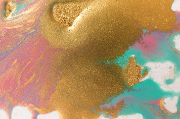 Piles of gold sequins on pink and blue smudges of paint. Abstract pattern.