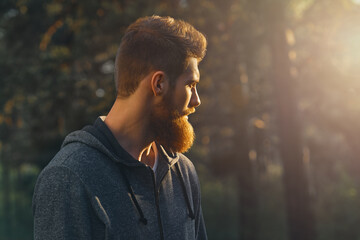 Profile young handsome serious bearded man. Hipster walking in a park. Portrait of man looking at...