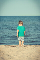 Baby boy walking and playing at summer beach. Vacation time and child development concept