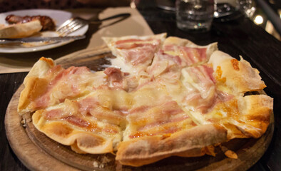 bacon pizza on wooden plate in restaurant