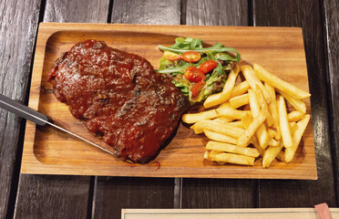 top view of barbecue pork ribs with fries and tomatoes on wooden plate