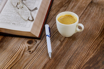 Personal study with Holy Bible with black coffee cup on pen with eyeglasses over wooden background