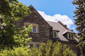Top of an old brick church building surrounded by green trees