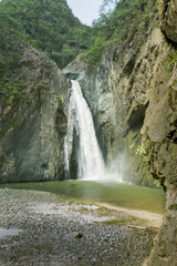 jimenoa waterfall landscape shot from behind the rocks in foreground.jimenoa waterfall it is a touristic destination in jarabacoa dominican republic