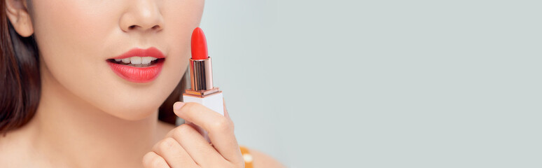 Portrait of a young beautiful woman applying lipstick for lips on a white background.