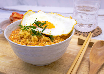 Spicy ramen (noddle) on a wooden board with a side dish (Kimchi).