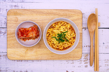 Spicy ramen (noddle) on a wooden board with a side dish (Kimchi).