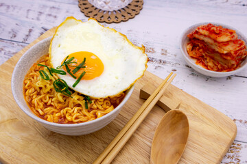 Spicy ramen (noddle) on a wooden board with a side dish (Kimchi).