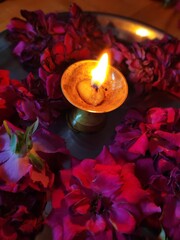 Red rose flowers over yellow background with diwali diya kept in the middle.