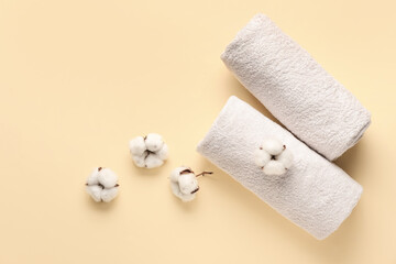 Cotton flowers and soft towels on color background