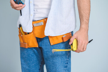 Young man with measuring tapes on light background, closeup
