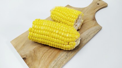 Close up fresh yellow sweet corn on cutting board isolated on white background