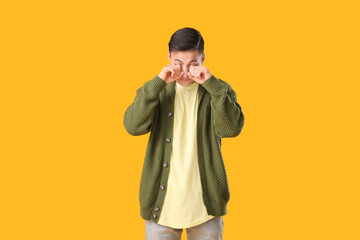 Young man suffering from sleep deprivation on color background