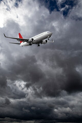 Commercial passenger plane with landing gear down flying through dramatic storm clouds