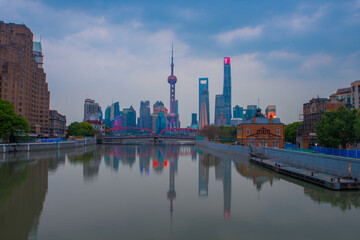 Fototapeta premium Zachód słońca widok na most Waibaidu i Lujiazui, panoramę i punkt orientacyjny w Szanghaju w Chinach, z odbiciem z przodu.