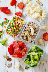 Frozen vegetables. Stocks of food for the winter. Container with frozen vegetables and mushrooms. Top view flat lay background.