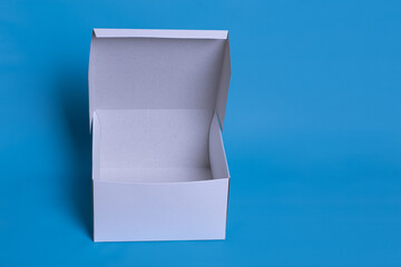 Close up photo of an open white box with shadow on a dark blue background. Clear simple template for packaging design
