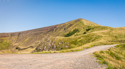 View of green mountains with a dirt road in southern Chile