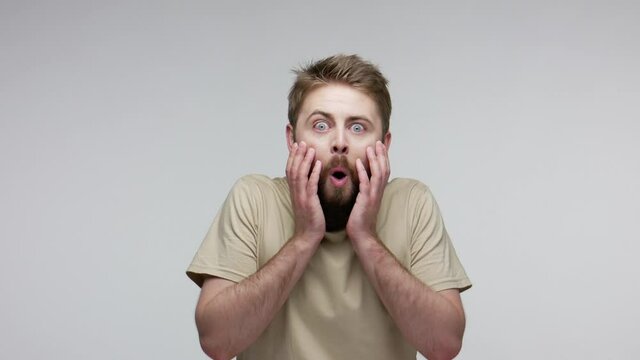 Wow, unbelievable! Bearded man raising hands with shocked expression, looking big eyes surprised at camera, opening mouth in amazement, disbelief and happy reaction on face. studio shot isolated