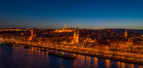 Aerial drone shot of St. Anne Parish church by Danube river at Budapest dusk city lights on