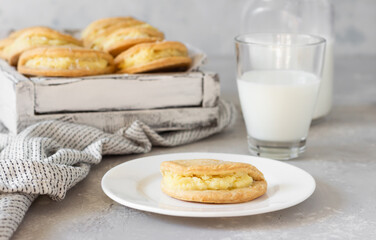 Homemade buns or pastries with cottage cheese on a wooden tray, light grey stone background. Traditional Russian pastry Sochnik.