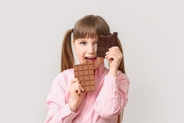 Cute funny girl with chocolate on light background