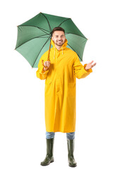 Young man in raincoat and with umbrella on white background