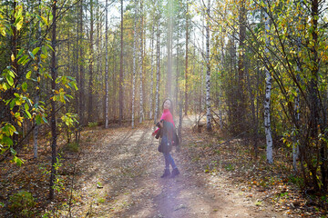 Obraz premium Beautiful young woman walking in the forest with sprice in autumn