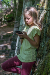 Porträt eines jungen, hübschen, manchmal nachdenklich oder frechen Mädchens beim Telefonieren oder spielend mit einem Mobil oder Smartphone.