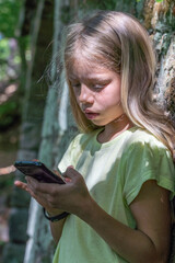 Porträt eines jungen, hübschen, manchmal nachdenklich oder frechen Mädchens beim Telefonieren oder spielend mit einem Mobil oder Smartphone.