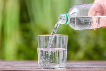 Pouring of water into glass on table outdoors