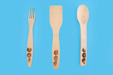 Wooden spoon, fork and spatula isolated on blue background. Top view. Kitchen utensils.