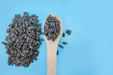 sunflower seeds in a wooden spoon on a blue background. . A bunch of seeds. Copy of space. View from above.