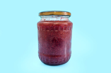 jar of strawberry jam isolated on a blue background. Copy of space.