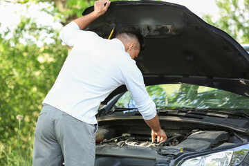 Young man near broken car on road