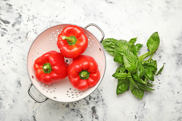 Red bell pepper and basil in colander on table