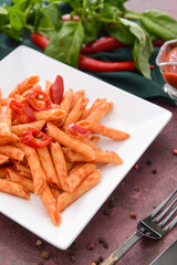 Plate with tasty pasta and tomato sauce on color background