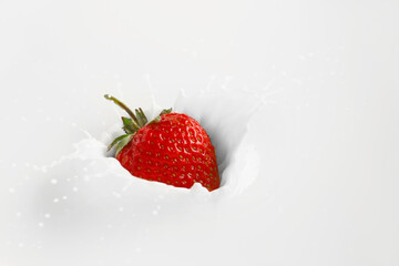 Falling of fresh strawberry into milk