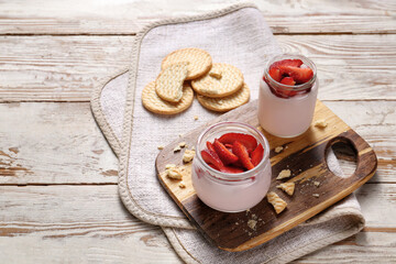 Jars of healthy strawberry yogurt on table