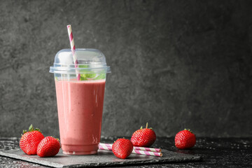 Cup of tasty strawberry smoothie on dark background