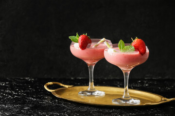 Glasses of tasty strawberry smoothie on dark background