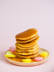 Pancake stack on wooden plate and pink background.