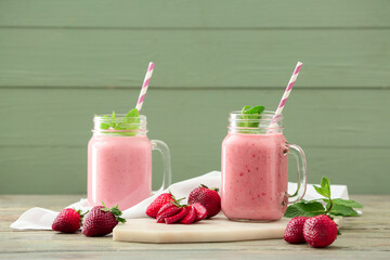 Mason jars of tasty strawberry smoothie on table