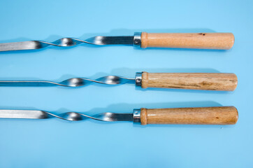 Three skewers isolated on a blue background. Close-up.